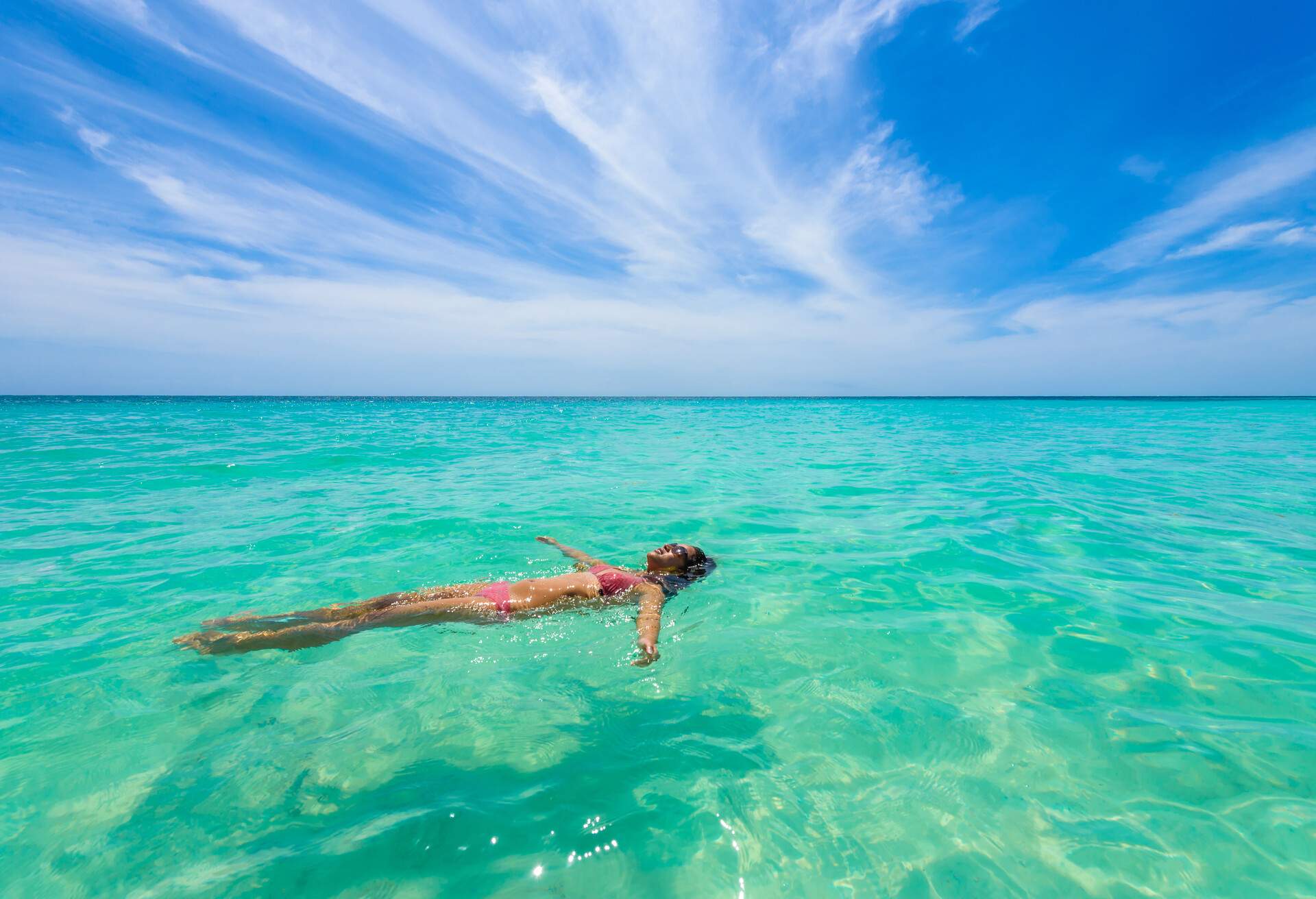 Attractive young woman relaxing in turquoise waters of Caribbean Sea in front of paradise beach in Tulum, close to Cancun, Riviera Maya, Mexico; Shutterstock ID 1036747504